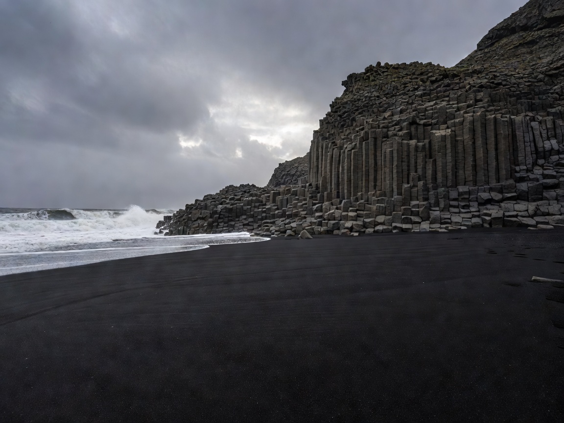 Moody volcanic black sand and geometric basalt columns of Reynisfjara beach Vik Iceland